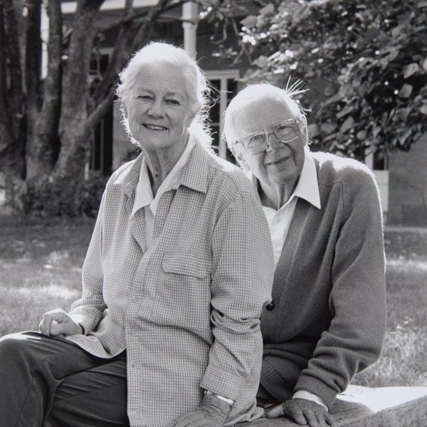Black and white photo of Arthur and Yvonne Boyd sitting in front of a sandstone house and trees