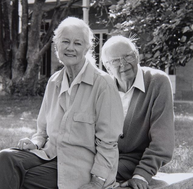 Black and white photo of Arthur and Yvonne Boyd sitting in front of a sandstone house and trees