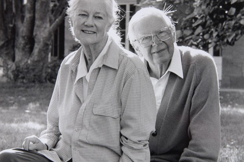 Black and white photo of Arthur and Yvonne Boyd sitting in front of a sandstone house and trees