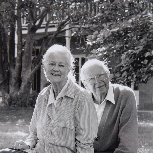 Black and white photo of Arthur and Yvonne Boyd sitting in front of a sandstone house and trees
