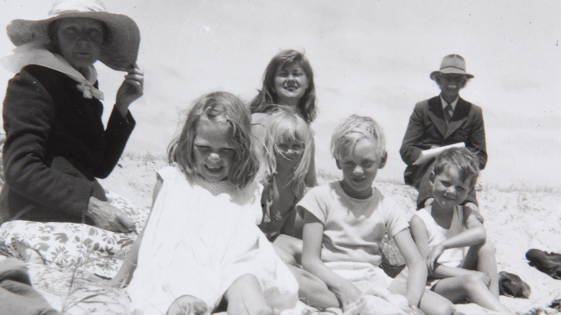 Black and white photo of a family sitting on a beach smiling