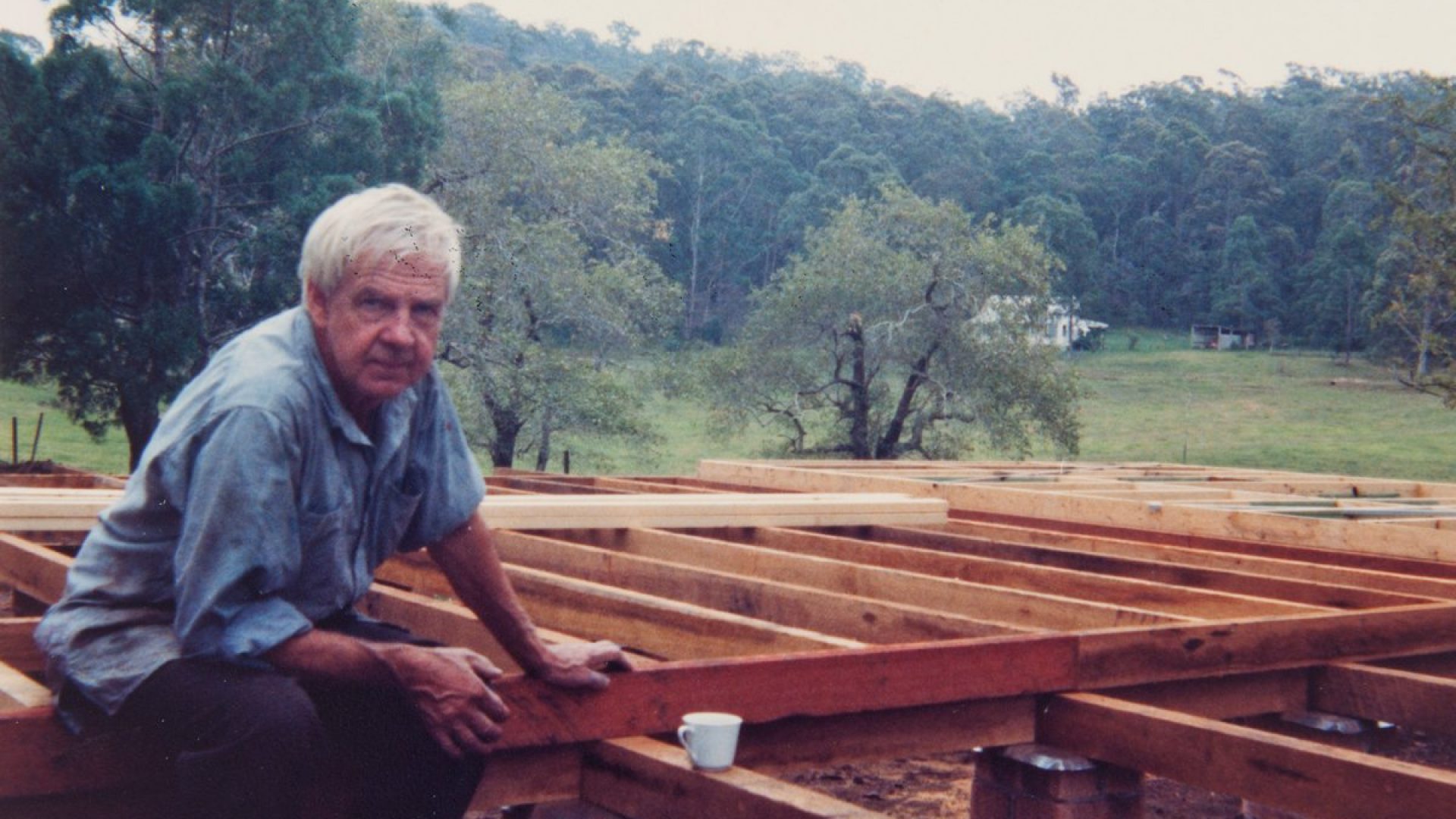 Arthur Boyd sitting on wooden beams at a construction site