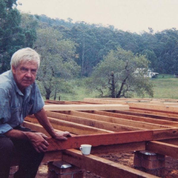 Arthur Boyd sitting on wooden beams at a construction site