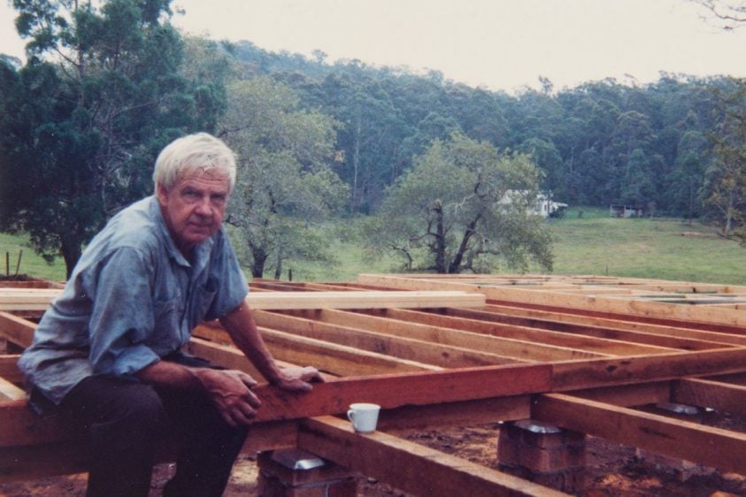 Arthur Boyd sitting on wooden beams at a construction site