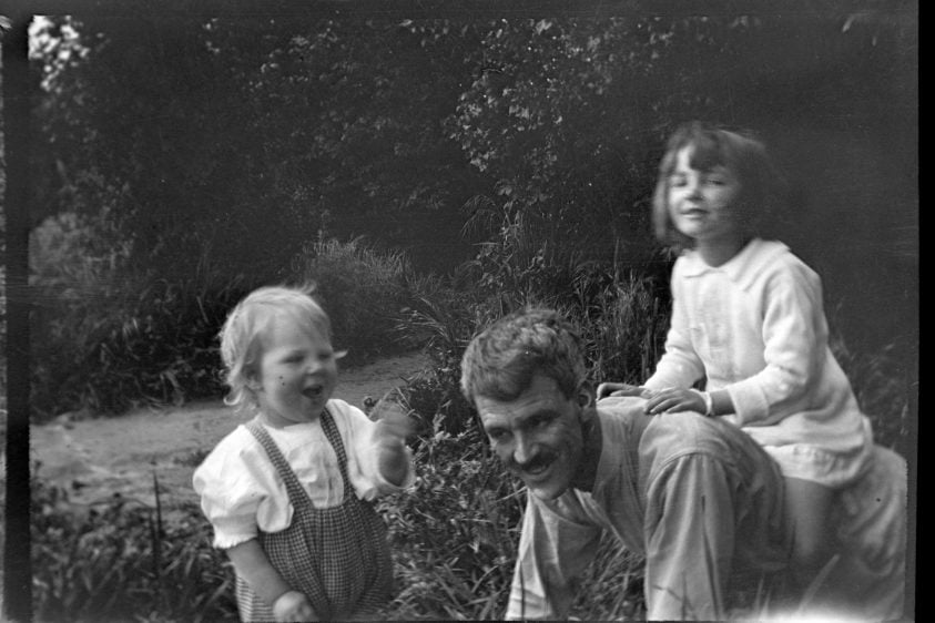 Photograph of a man and two young children playing outside