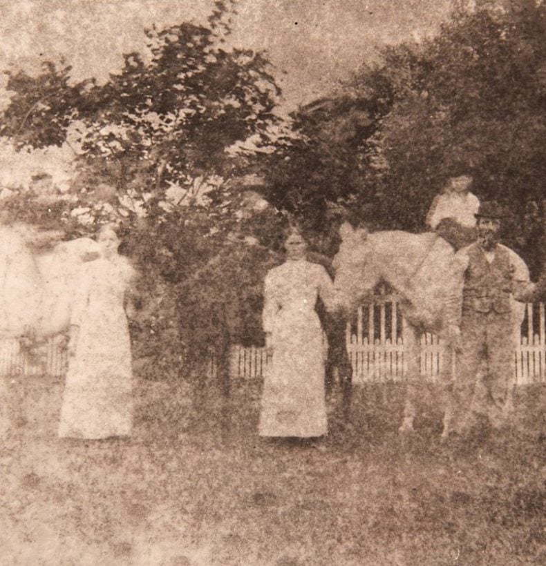 Old photo of three people standing with 4 horses