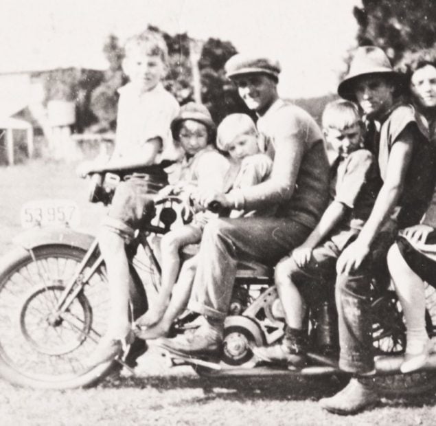 Old photo of two men, a woman and four children on a motorbike