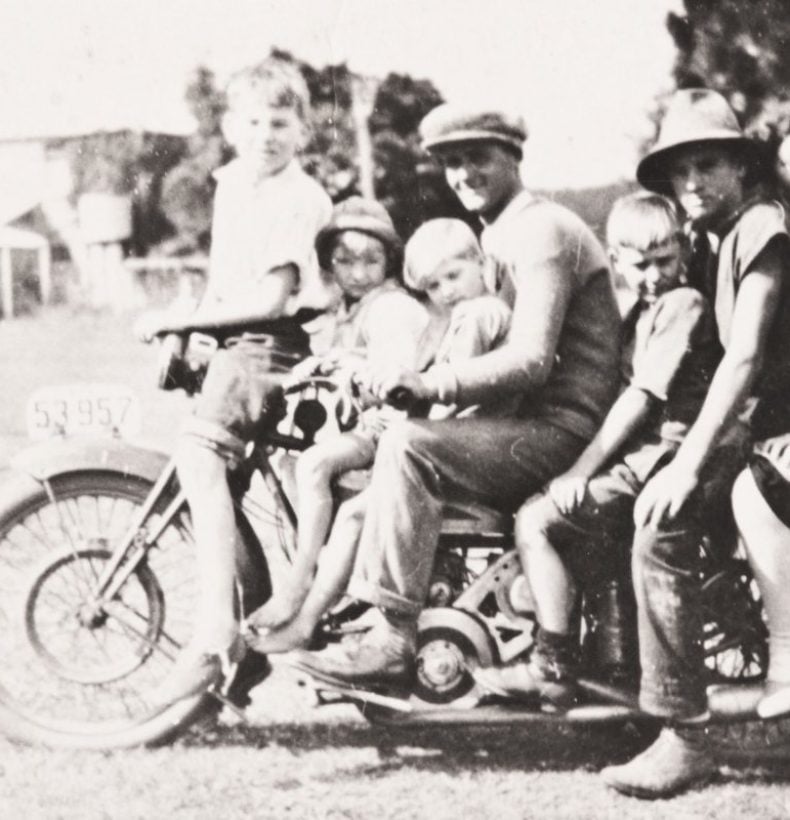 Old photo of two men, a woman and four children on a motorbike