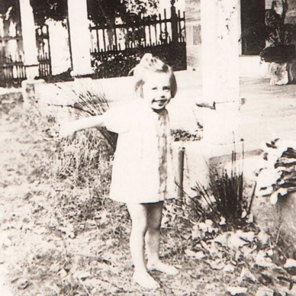 Old photo of a child standing out the front of a house