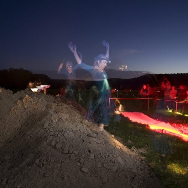 Photograph of a performer emerging from a pile of dirt