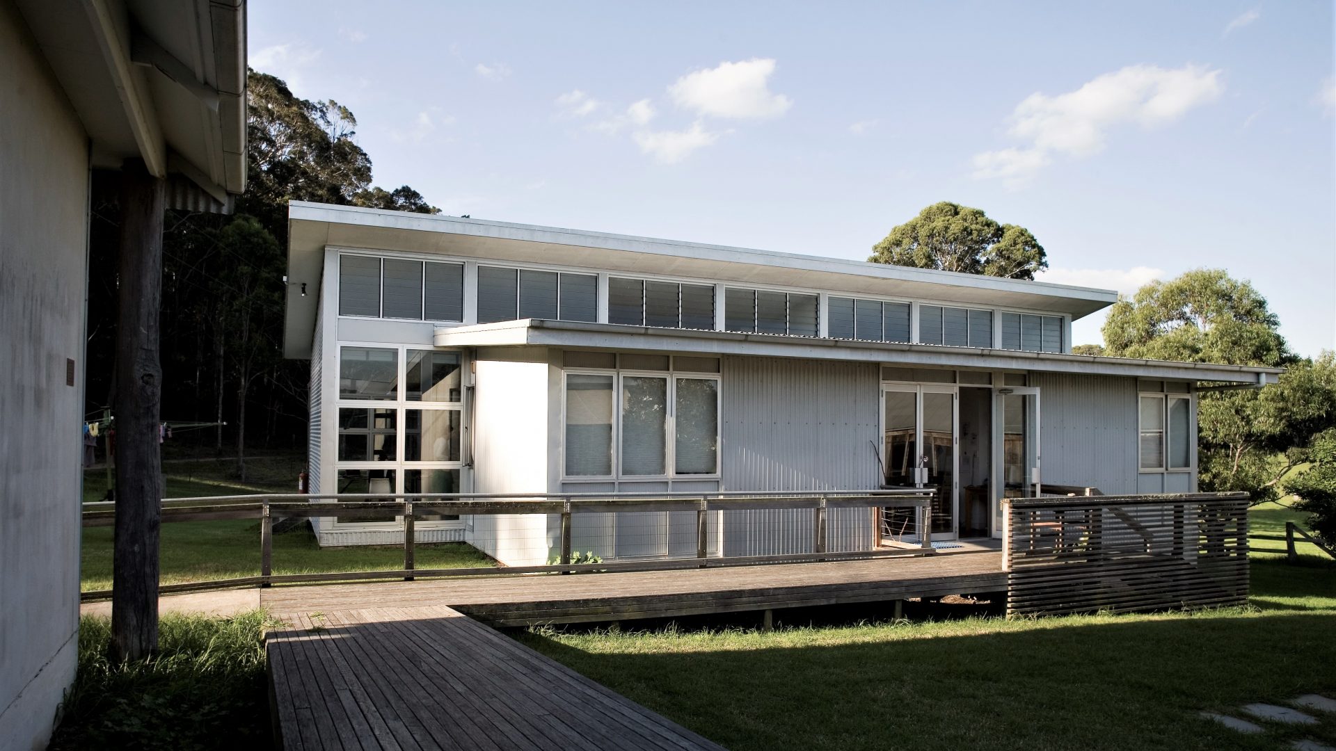 A grey metal building with wooden ramps and grass out the front.