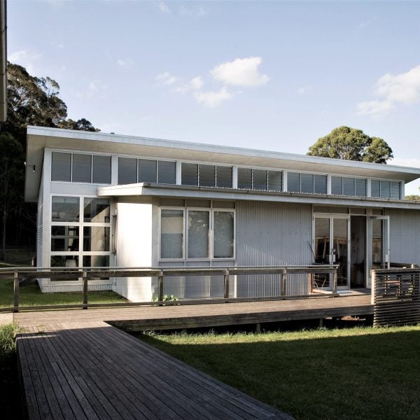 A grey metal building with wooden ramps and grass out the front.