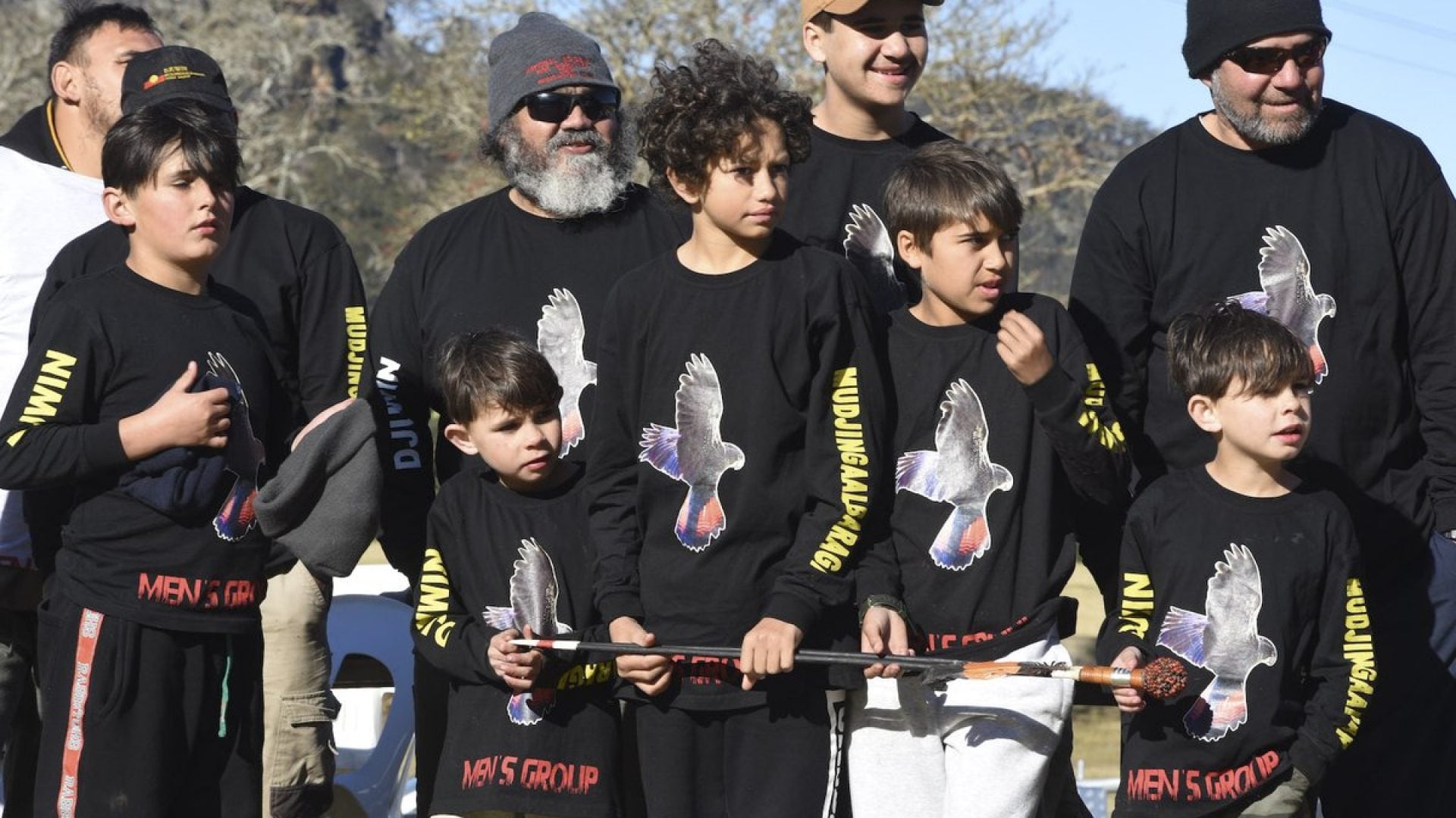 A group of young boys and men standing in black jumpers