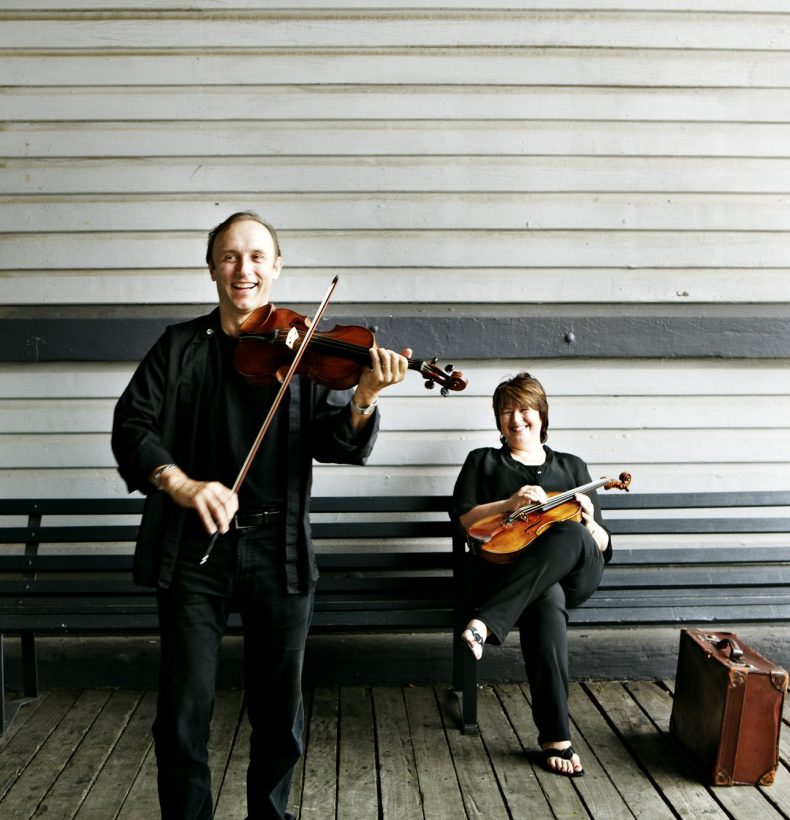 Musicians standing with their instruments in a shed space