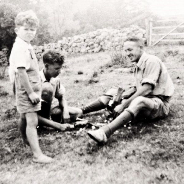 Black and white photo of a man and two children digging in the dirt