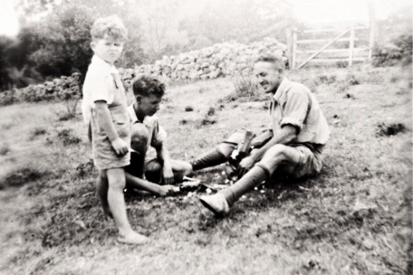 Black and white photo of a man and two children digging in the dirt