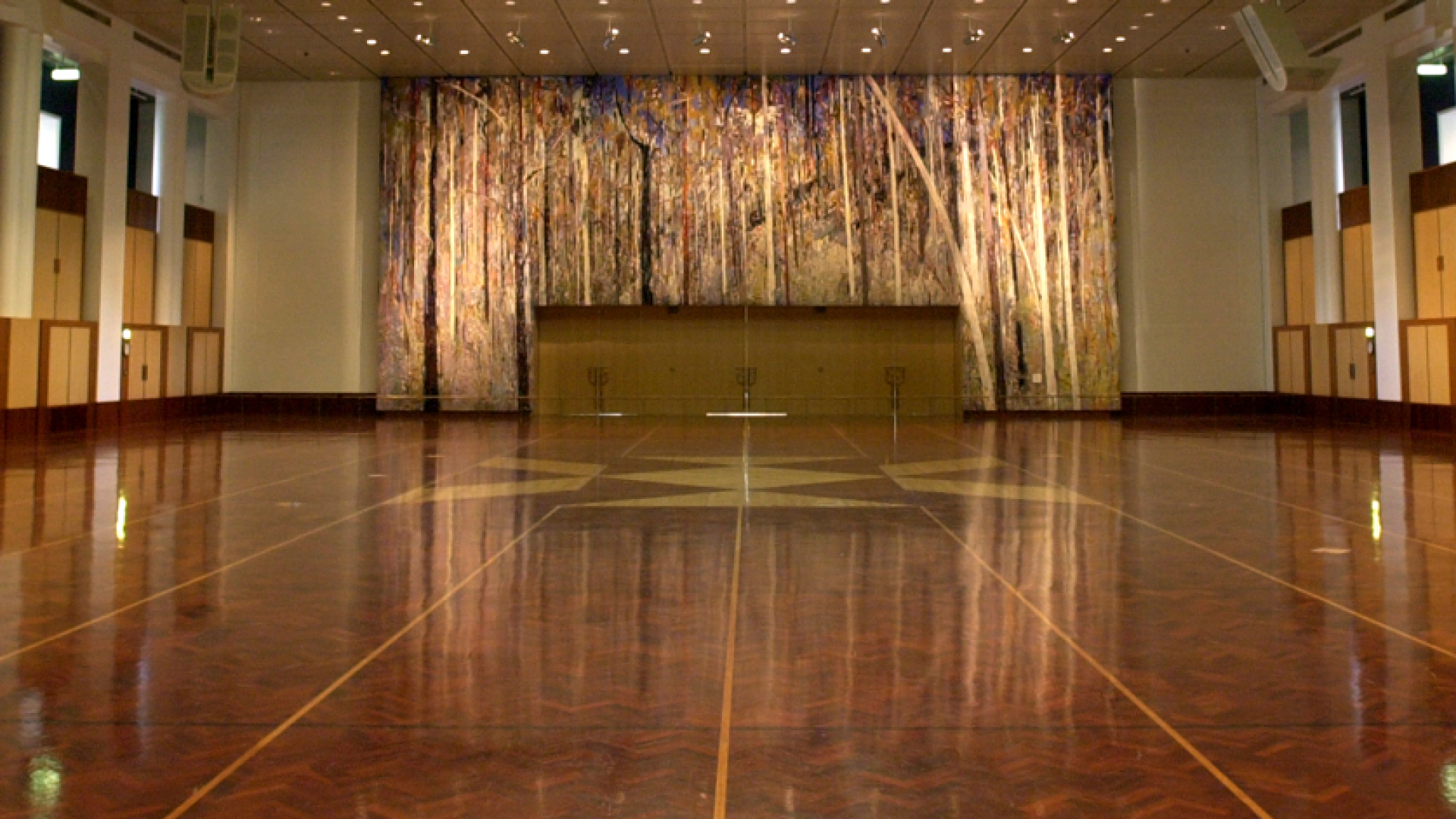 A large hall space with a tapestry on the back wall depicting a dense bushland