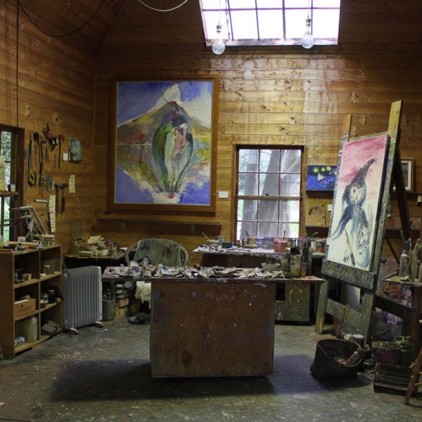 Inside an artist's studio. Pains on the benches and paintings hanging on the wall and easel