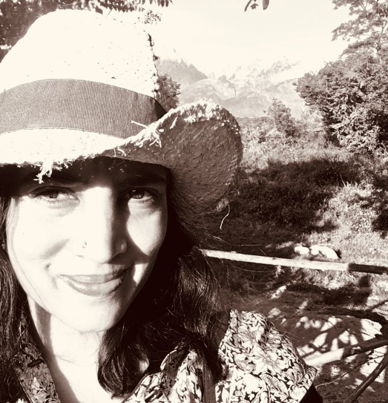 Black and white photograph of a person in a hat, smiling and looking into the camera