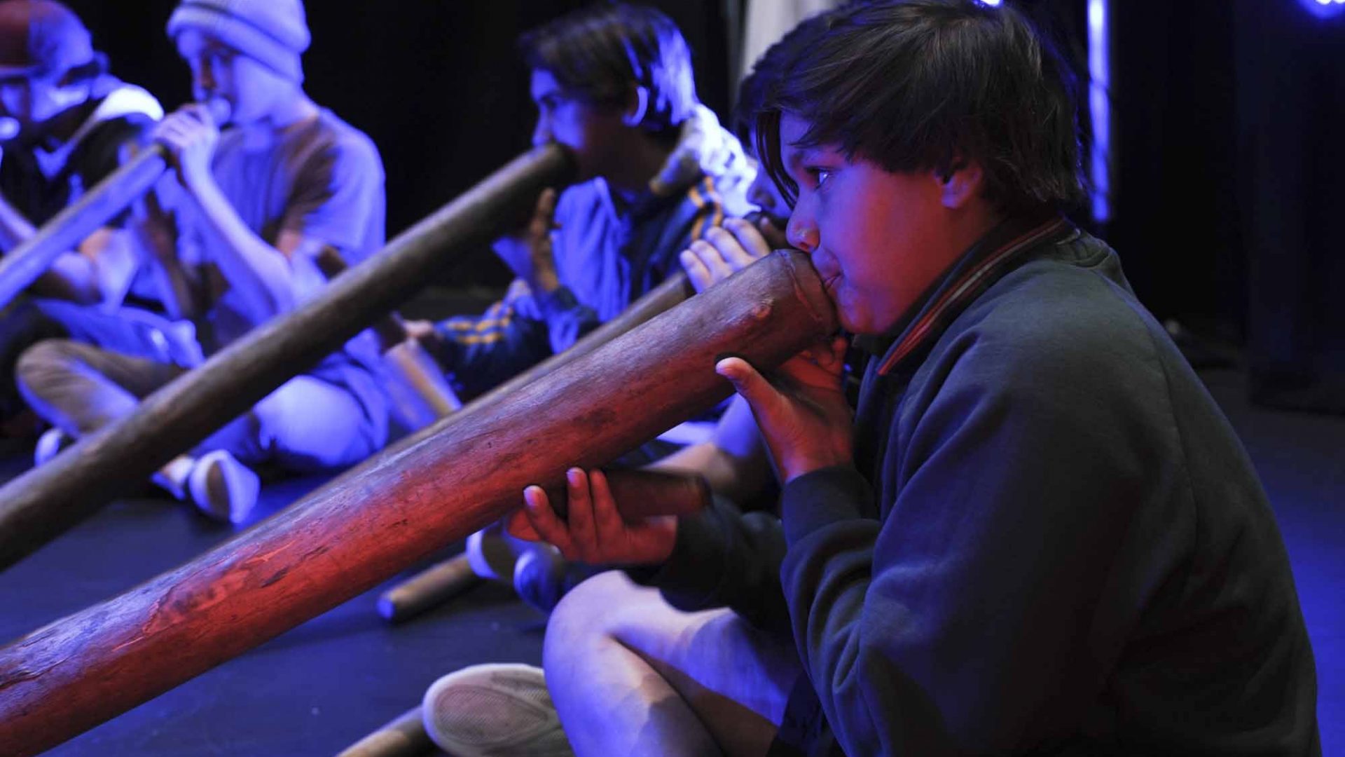 5 young boys playing the didgeridoo