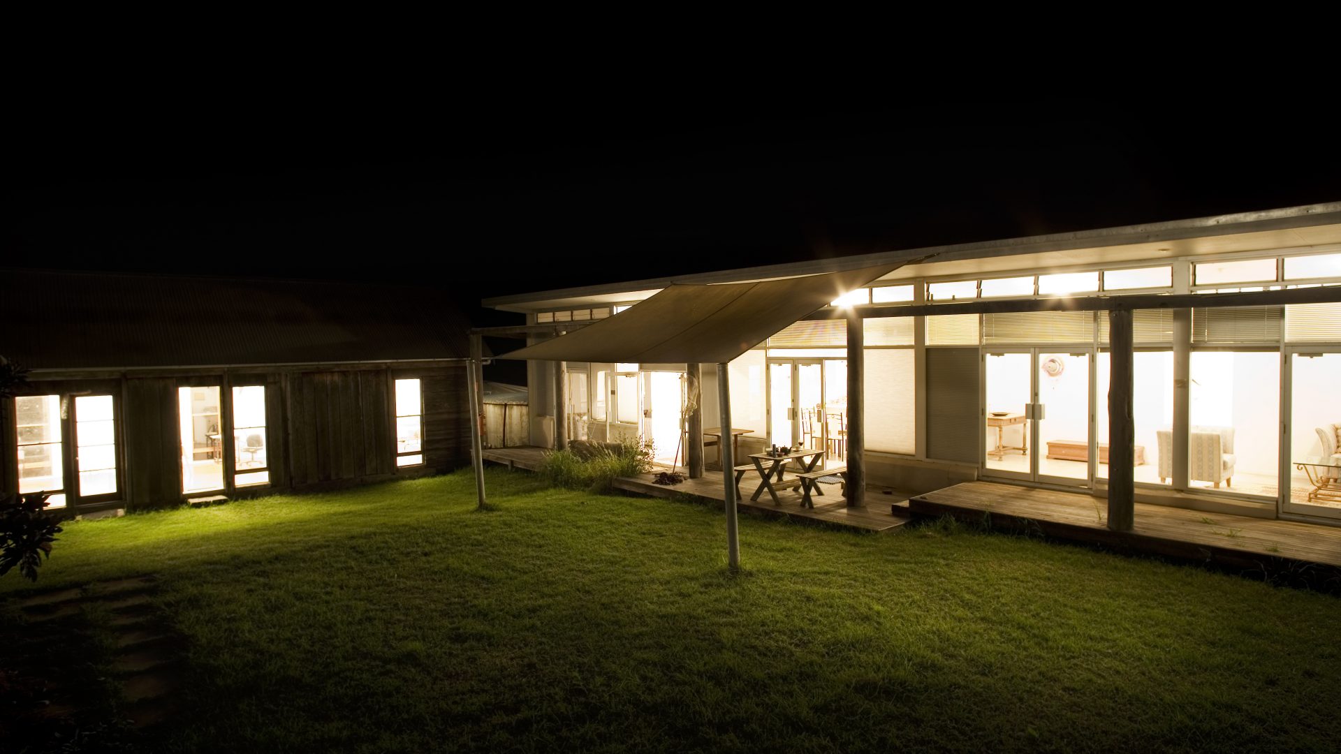 A photo of two buildings at nights. Lights inside the rooms illuminate them