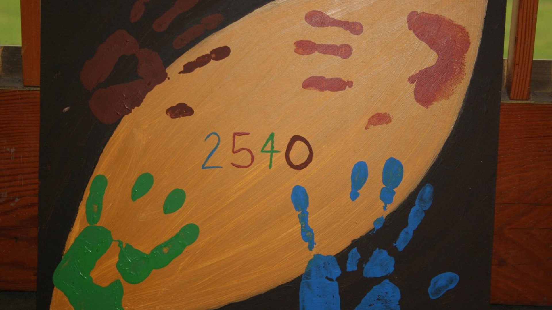 A painting with multi-coloured hand prints and the numbers 2 5 4 0 painted in the centre