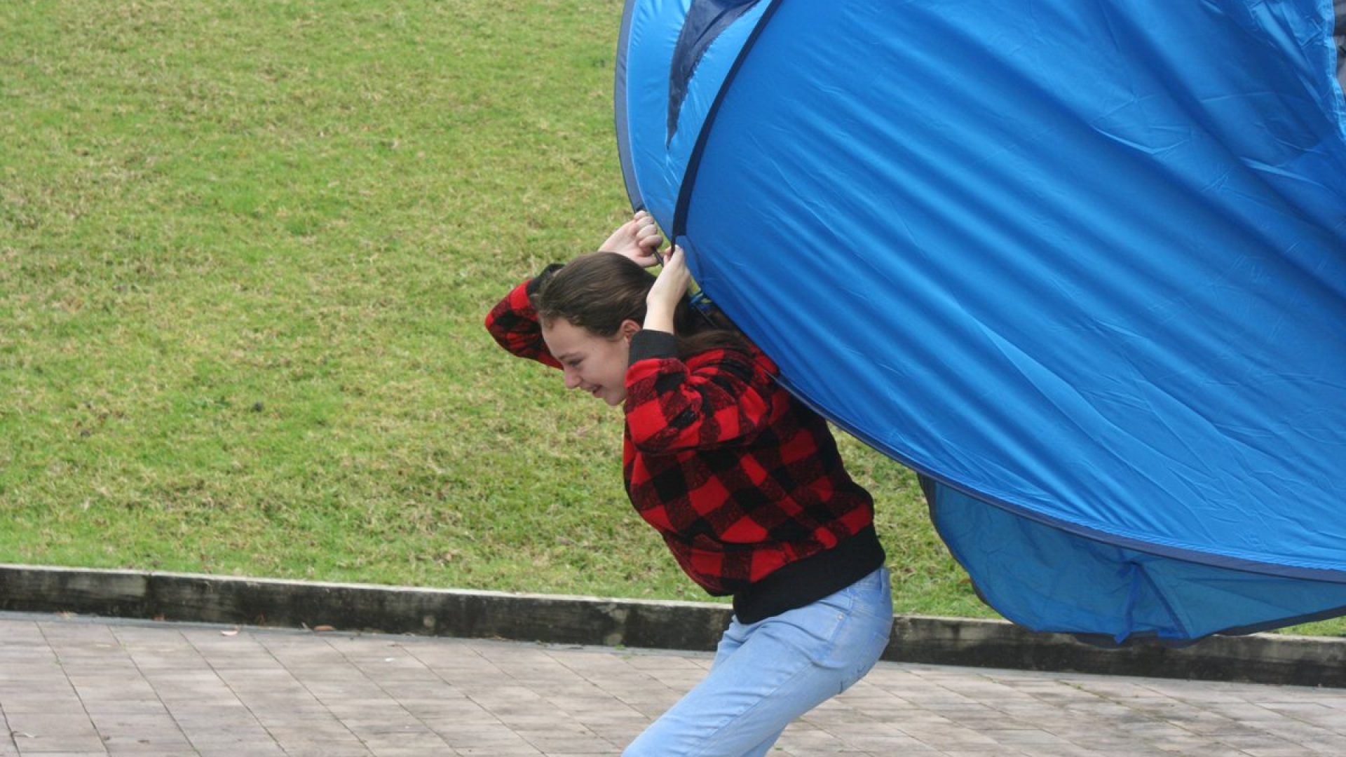 Person holding a large blue tent against their back