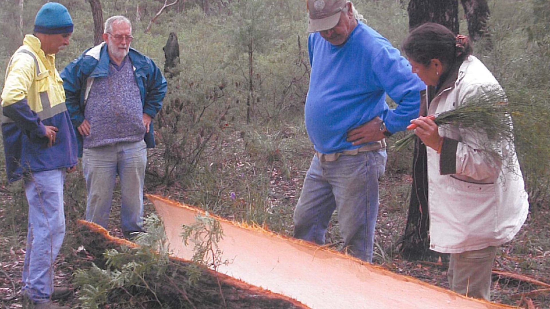 4 people building a small wooden canoe structure