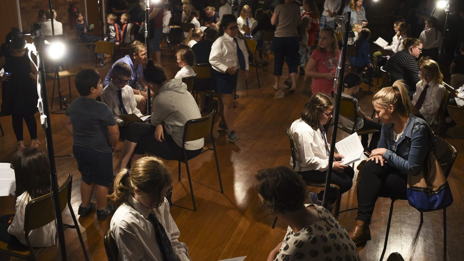 A room crowded with people sitting on seats have one-on-one conversations with each other