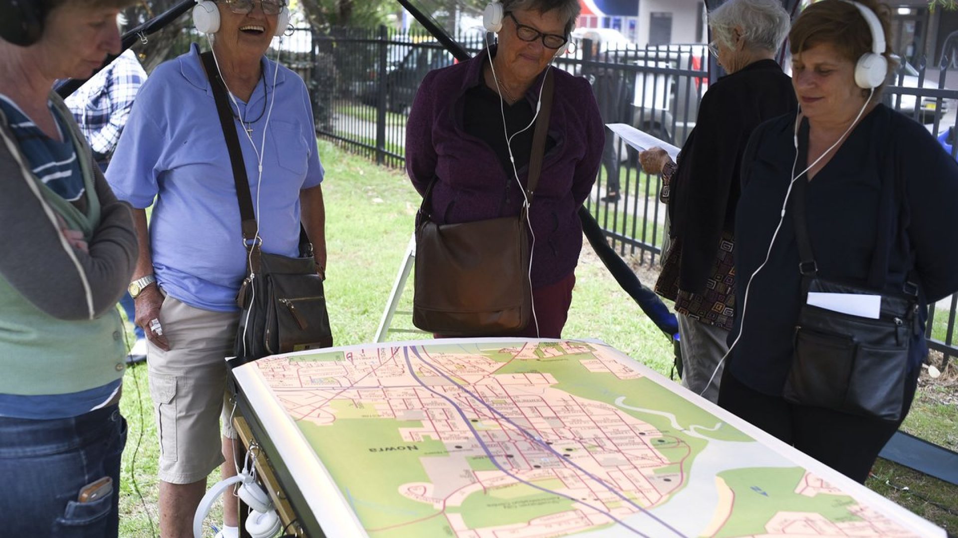 4 people wearing headphones standing around a table looking at a a map