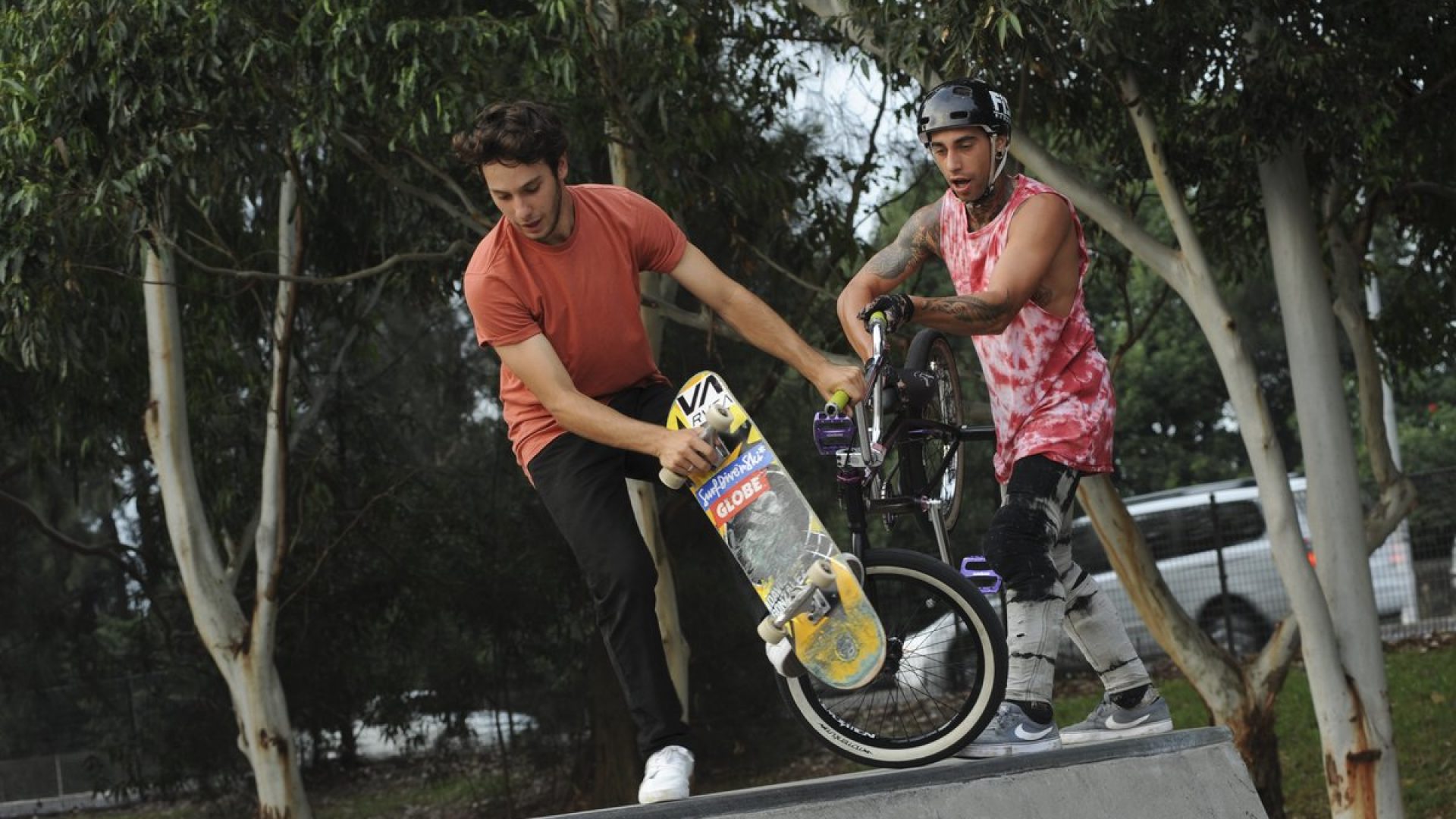 A skate boarder and a bike rider at a skate park