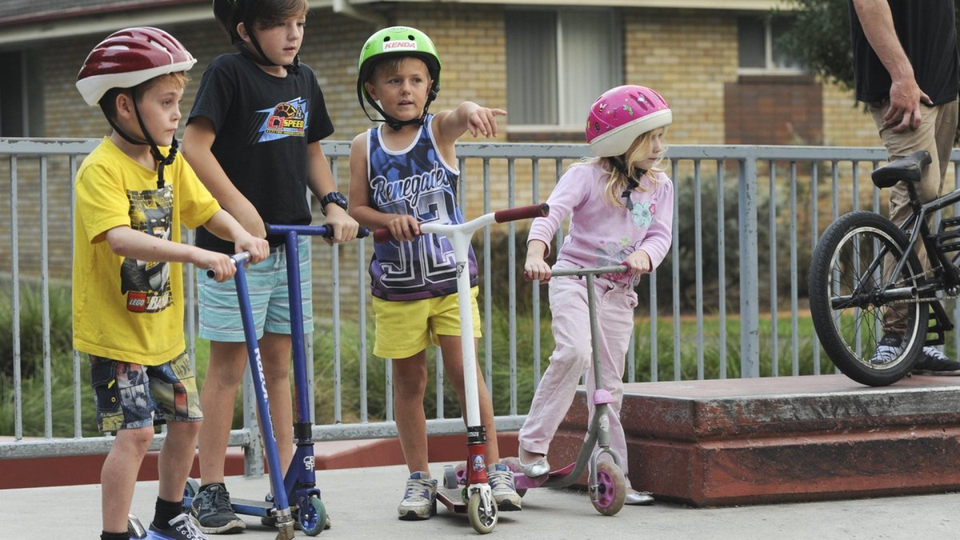 4 kids on scooters at a skate park