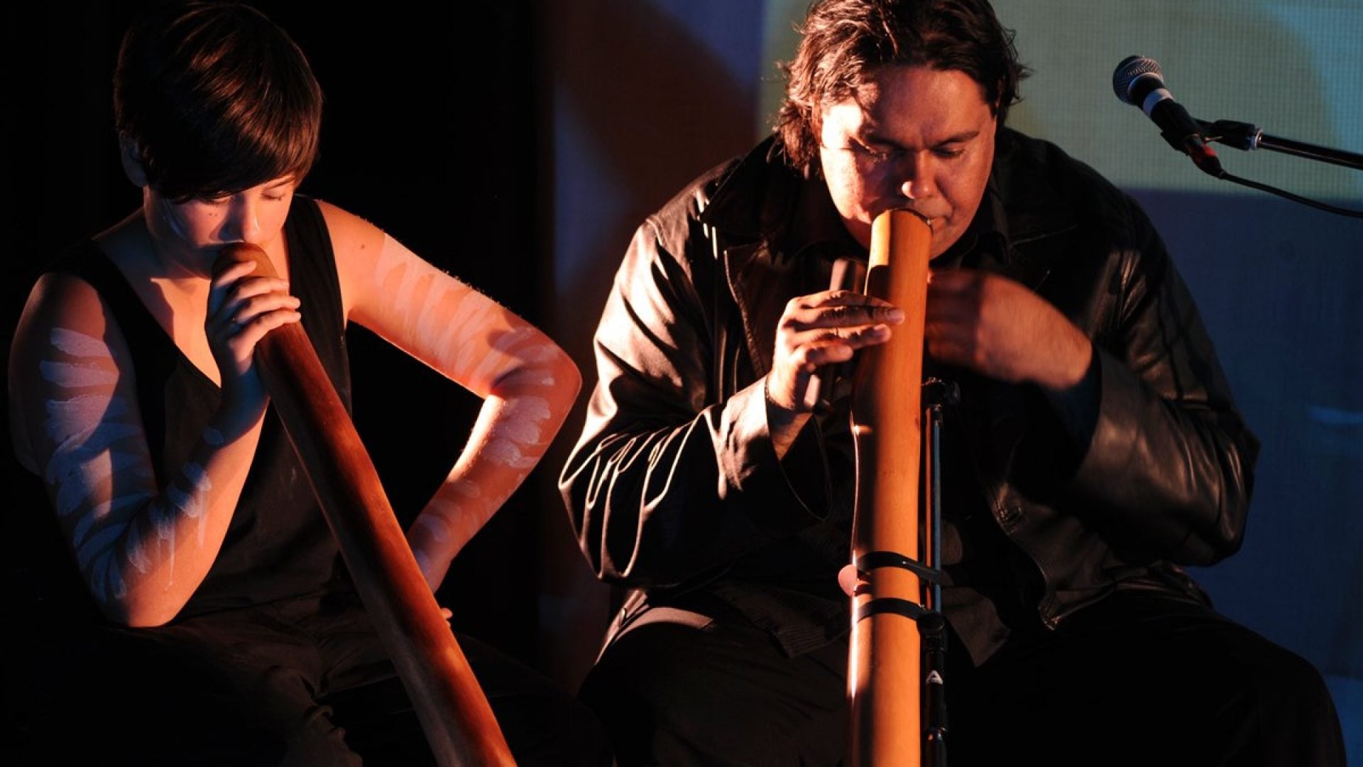 Two people playing didgeridoo