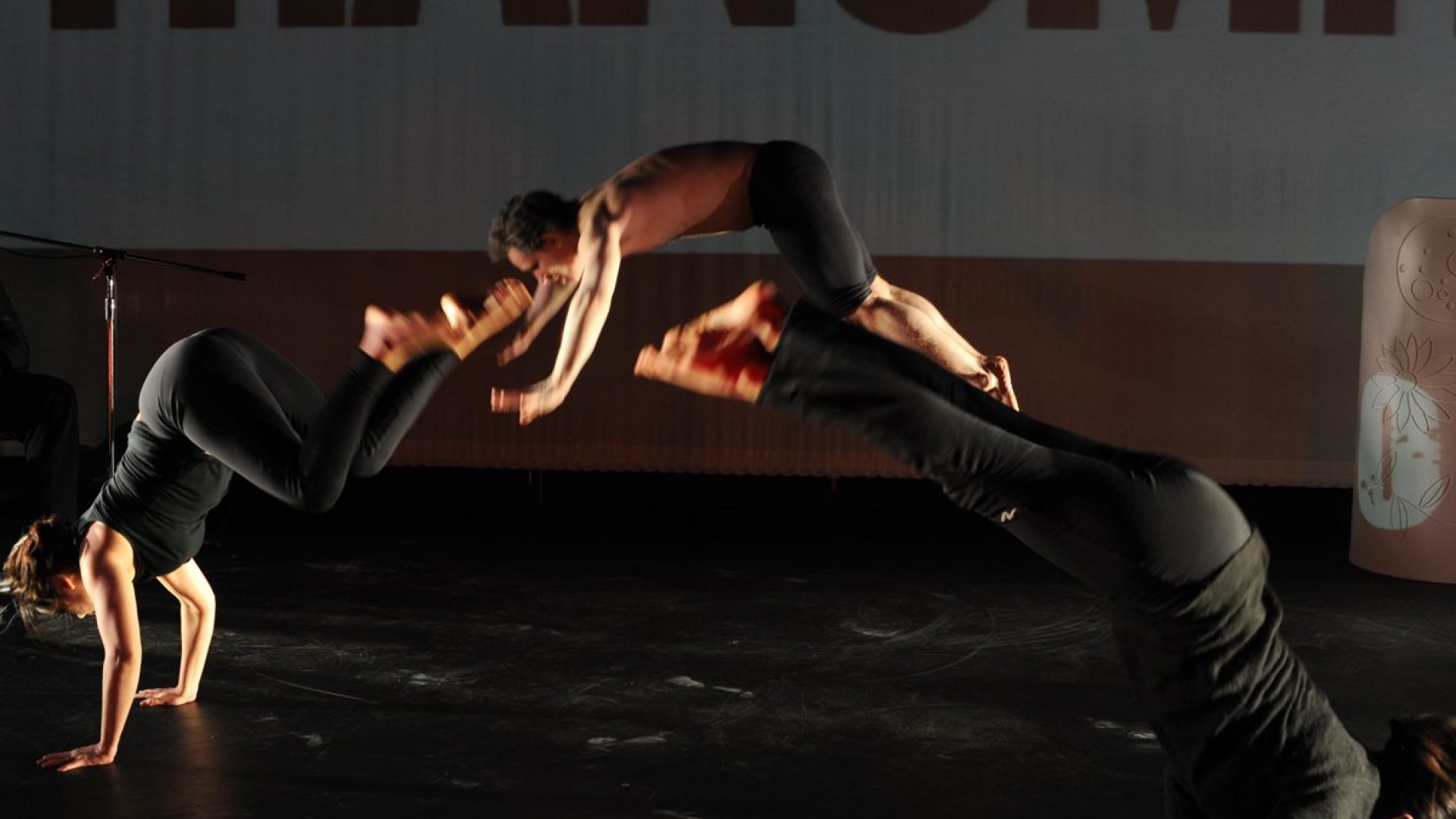3 dancers leaping across a stage