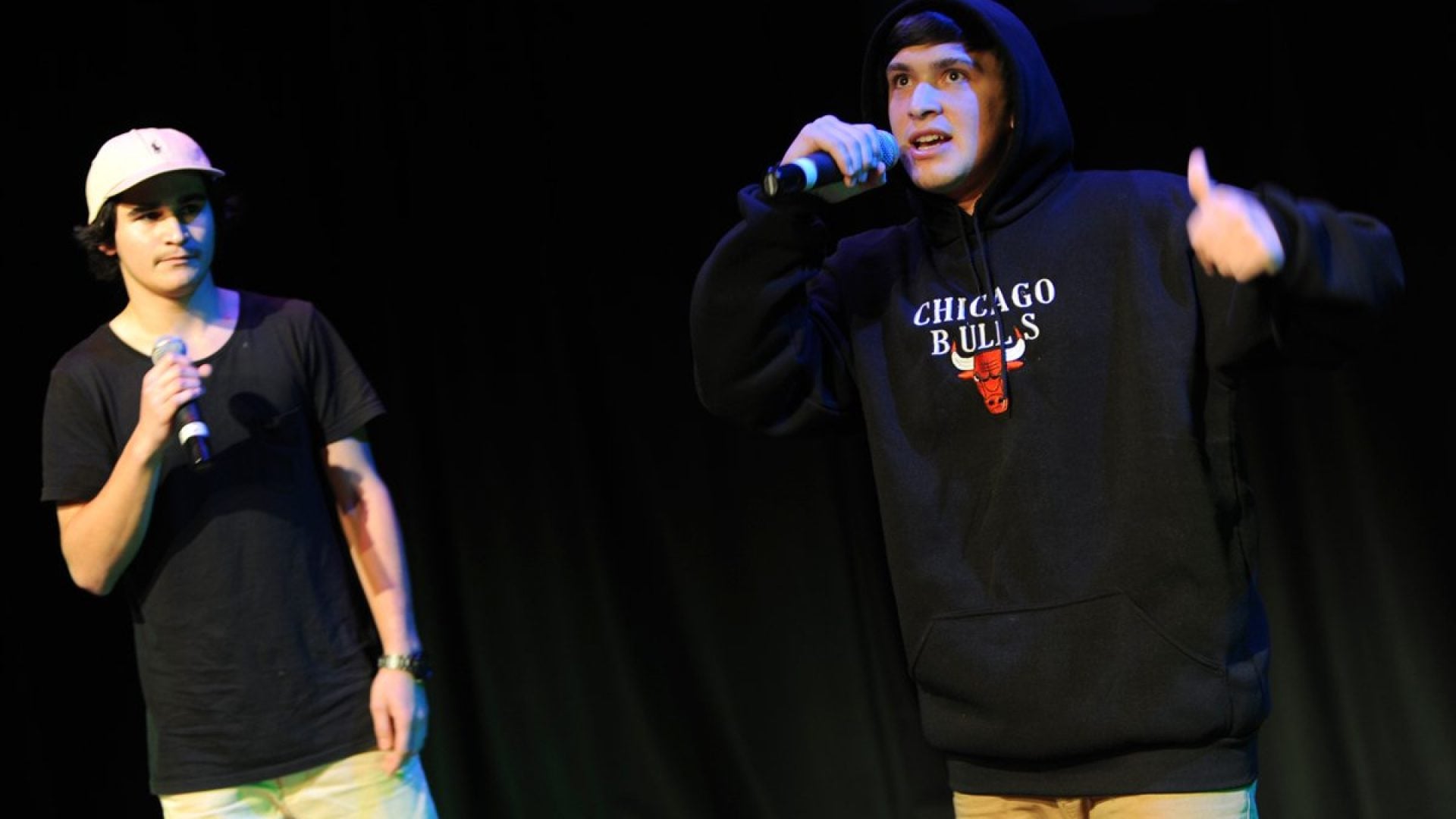 Two people moving around and singing into a microphone