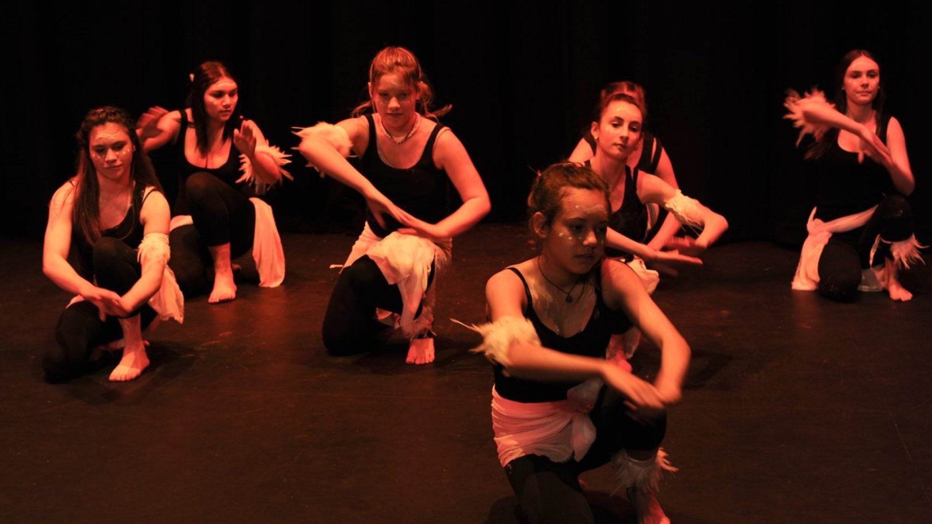 7 girls crouched down dancing on stage