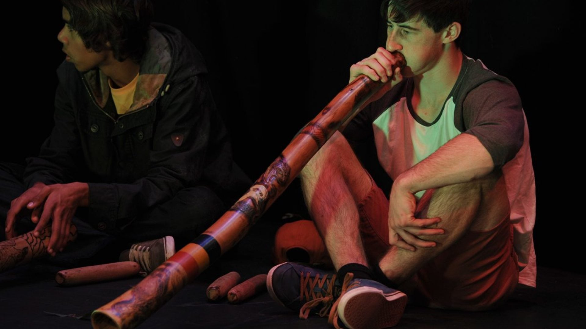 Person sitting down playing a didgeridoo