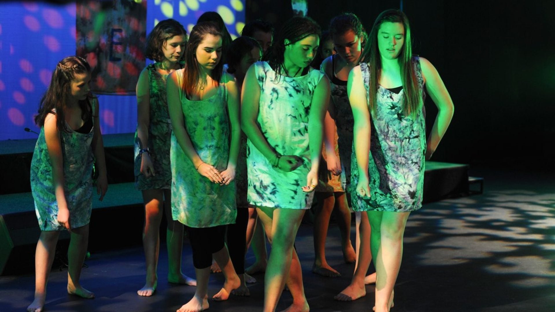 10 girls dancing closely together on stage