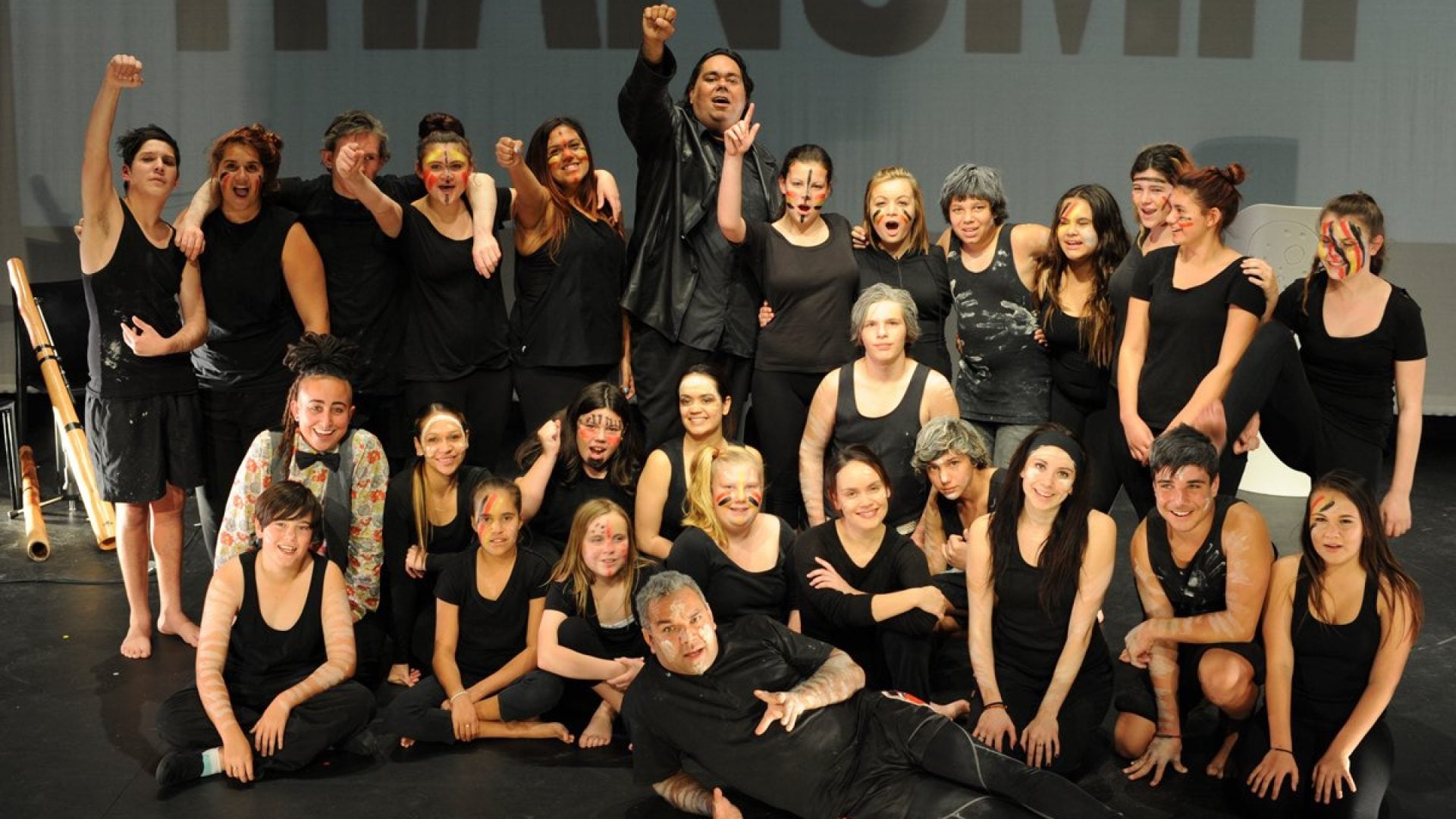 A ground of 20 dancers standing together, smiling