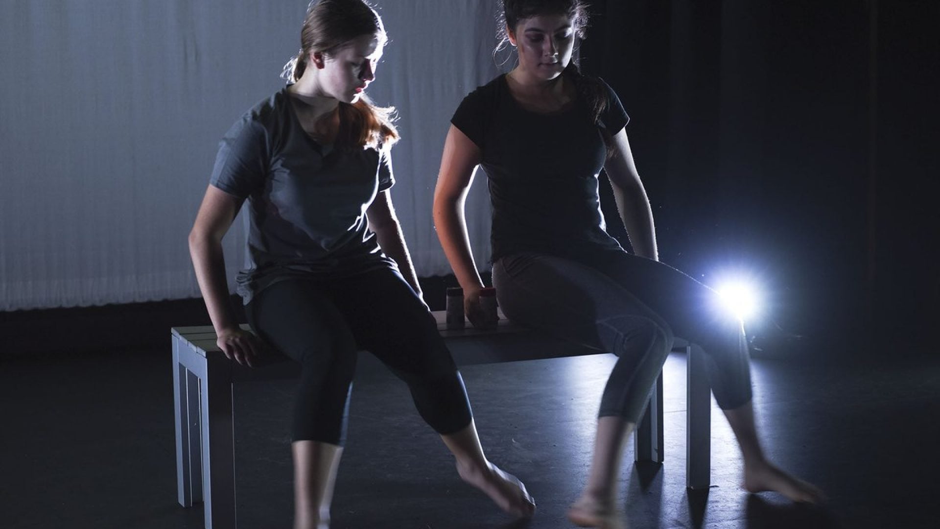 Two dancers sitting on a bench on a stage