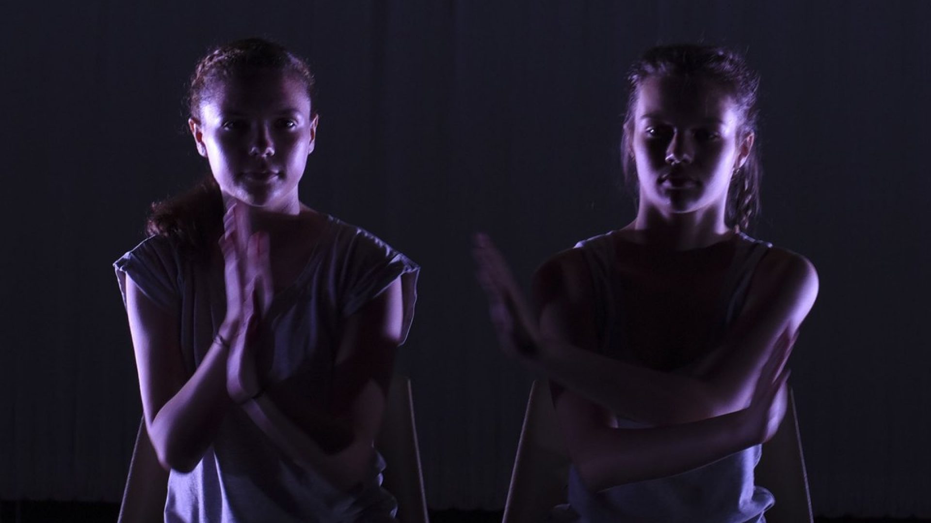 Two young dancers on a dark stage