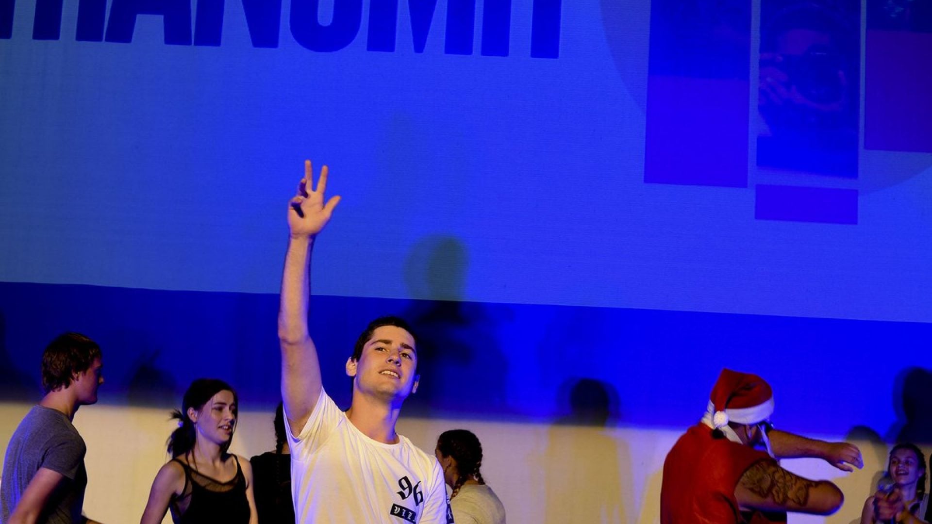 Group of people on stage with a person in the middle holding their hand in the air
