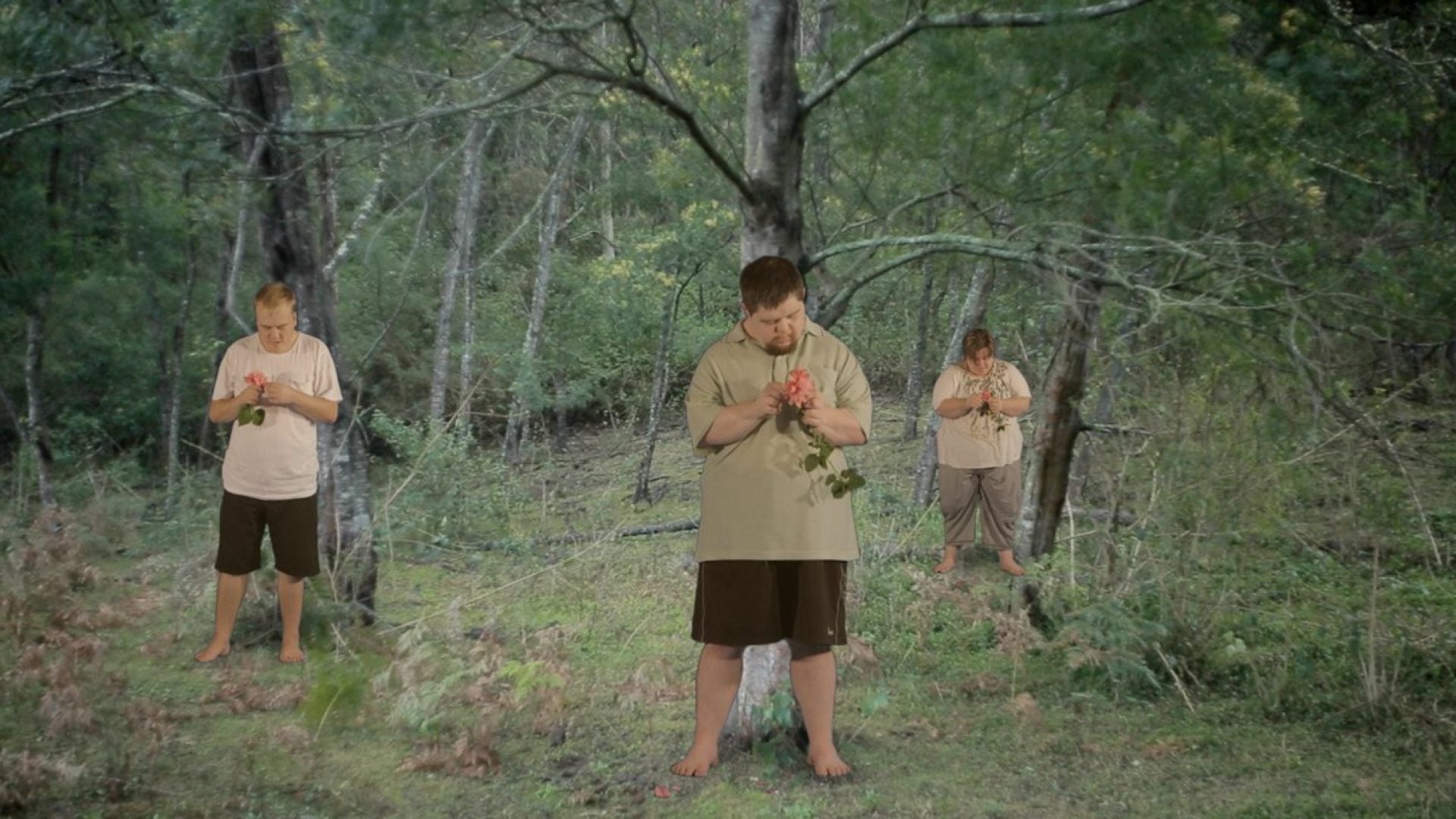 3 people holding roses standing in a forest