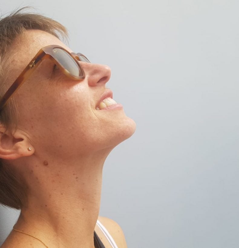 A person wearing sunglasses tilts their head to look above