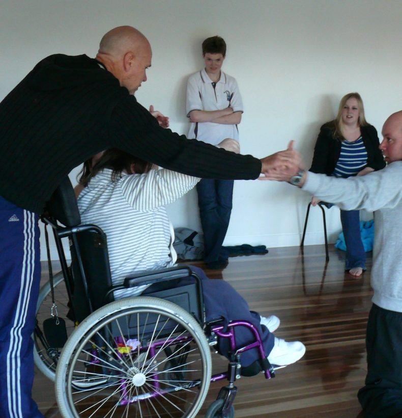 A person in a wheelchair with people standing around them