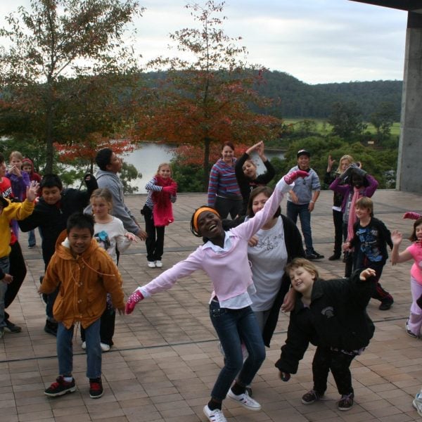 15 children jumping around with their arms in the air