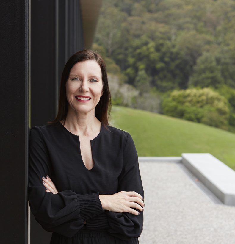 A person wearing a black shirt, leaning on a black pole