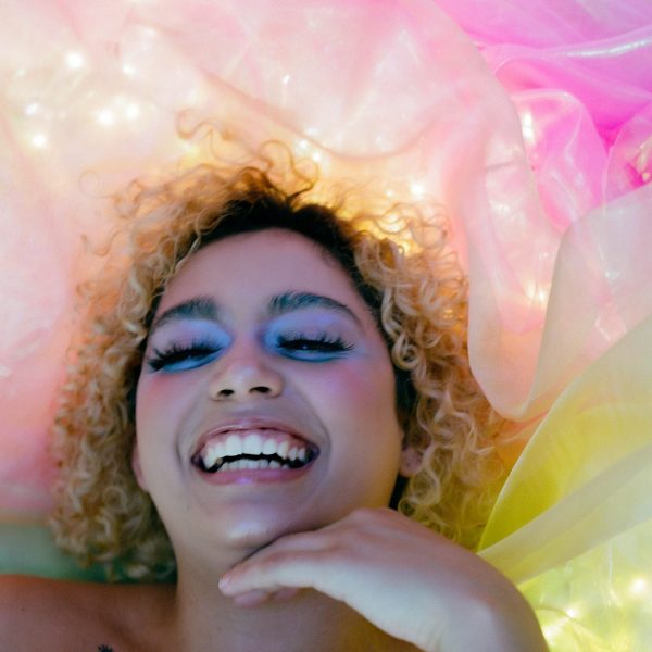 A person smiling with multi-coloured material behind their head