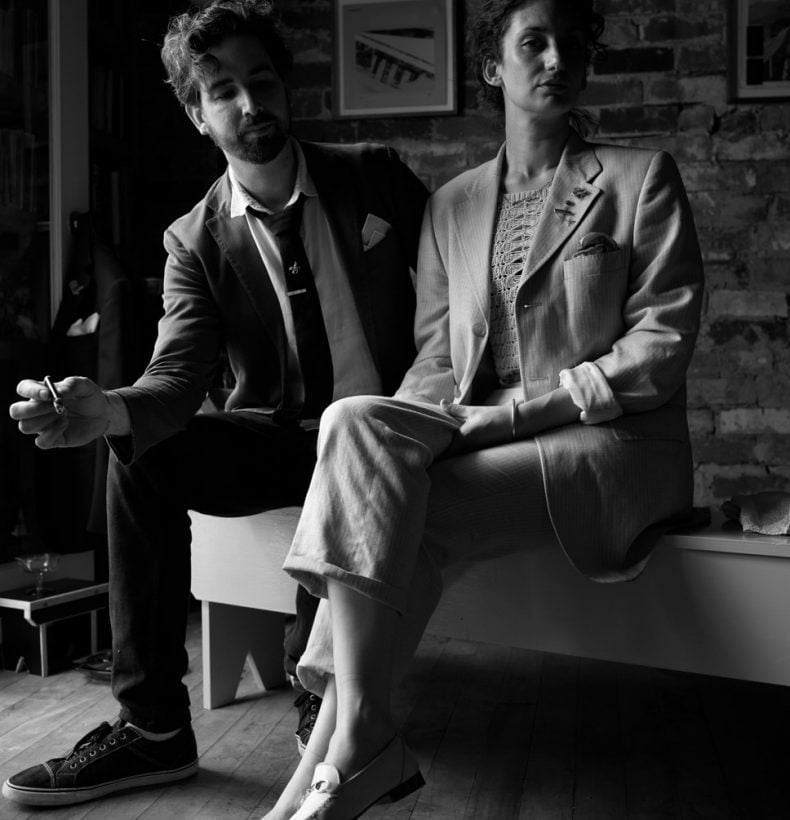 Black and white photo of 2 people sitting in suits.