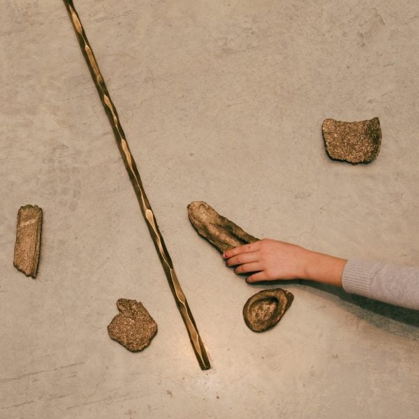 Brown objects on a grey floor with an arm extending and holding one